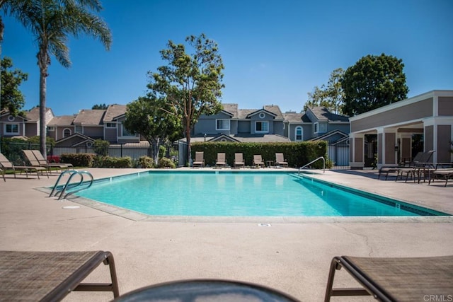 community pool with fence, a residential view, and a patio
