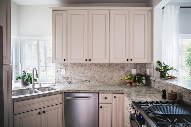 kitchen with decorative backsplash, light stone counters, a sink, and appliances with stainless steel finishes