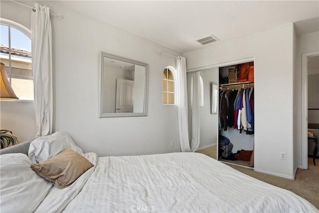 carpeted bedroom with visible vents and a closet