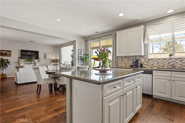 kitchen featuring stainless steel dishwasher, a sink, dark wood-type flooring, a center island, and open floor plan