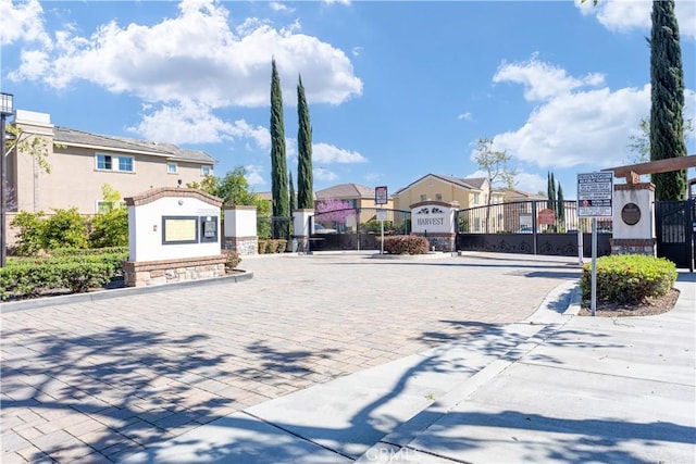 view of road featuring a gate, a gated entry, curbs, and a residential view