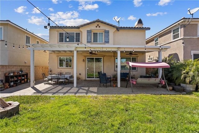 back of house with a ceiling fan, a pergola, stucco siding, a patio area, and a lawn