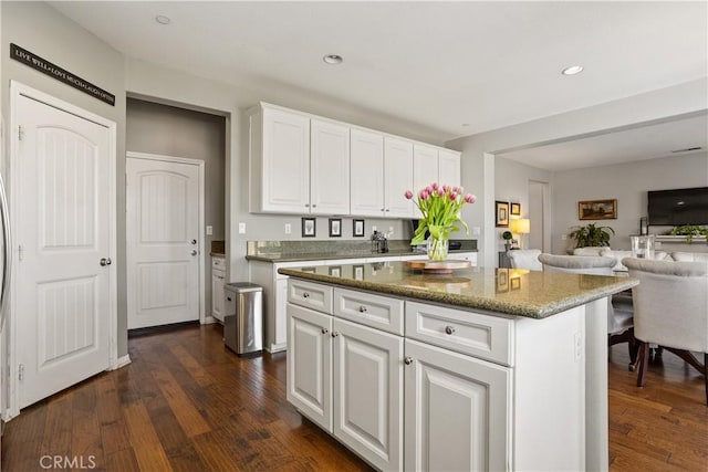 kitchen featuring open floor plan, white cabinets, dark wood-type flooring, a kitchen island, and recessed lighting