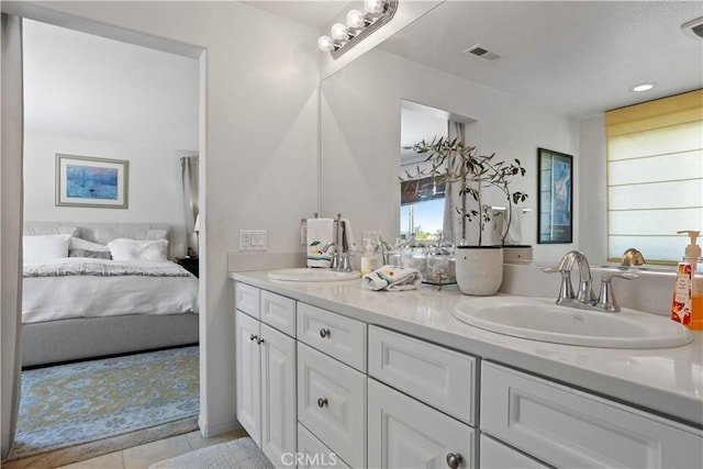 ensuite bathroom with double vanity, visible vents, tile patterned floors, and a sink