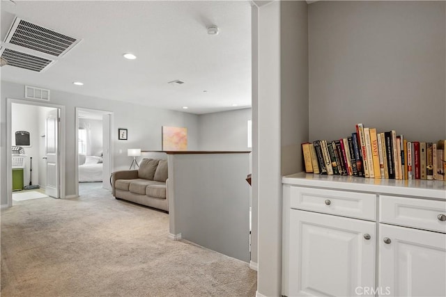 hallway featuring light carpet, visible vents, recessed lighting, and an upstairs landing