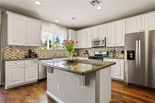 kitchen featuring stainless steel appliances, white cabinetry, dark wood-type flooring, visible vents, and a kitchen island