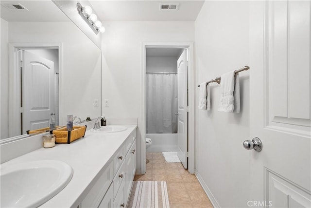 bathroom featuring double vanity, visible vents, toilet, and a sink