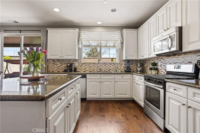 kitchen with stainless steel appliances, decorative backsplash, and white cabinetry