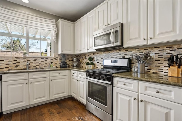 kitchen featuring white cabinets, decorative backsplash, stainless steel appliances, and a sink
