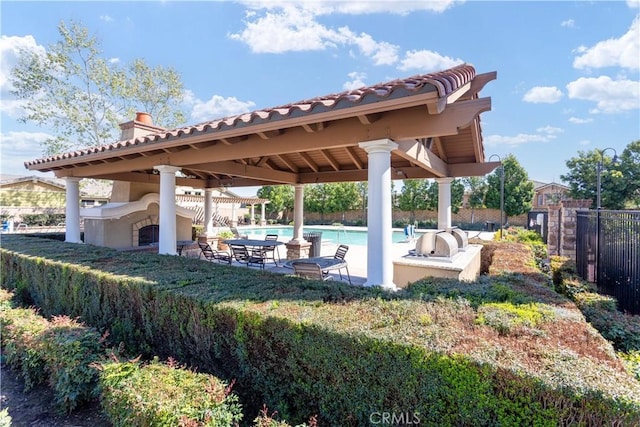 view of patio / terrace featuring exterior fireplace, a gazebo, fence, and a fenced in pool