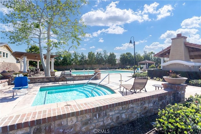 pool with fence, a hot tub, and a patio area