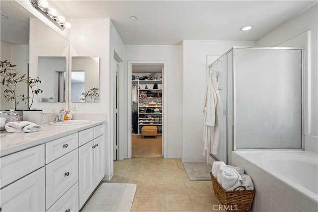 bathroom with a shower stall, a bath, a walk in closet, vanity, and tile patterned flooring
