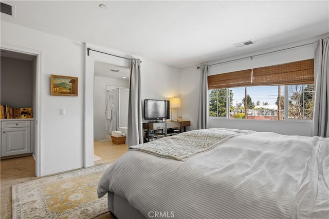 bedroom featuring visible vents, carpet flooring, and ensuite bathroom