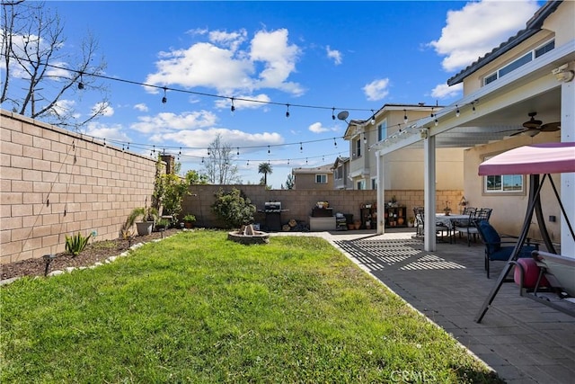 view of yard with a fenced backyard, a fire pit, a patio, and ceiling fan