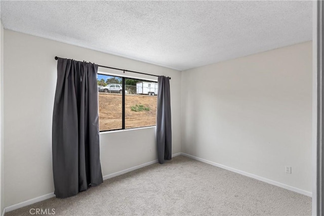 spare room featuring baseboards, a textured ceiling, and carpet