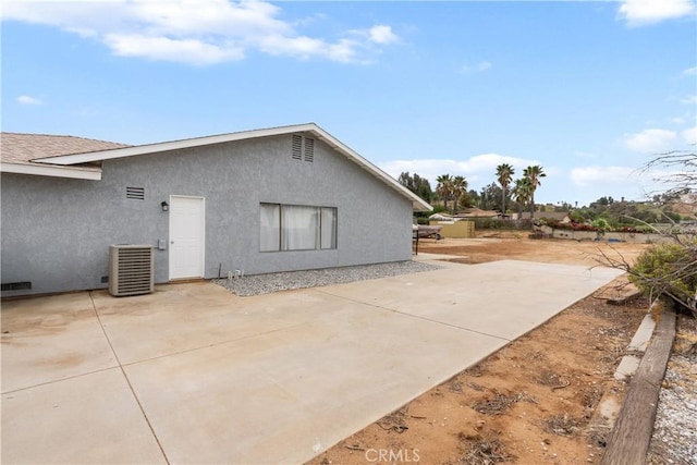 back of property with stucco siding, a patio area, and central AC