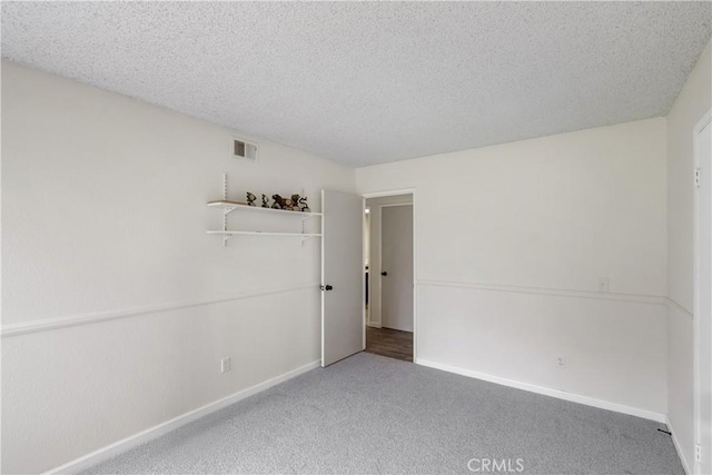 unfurnished room with visible vents, baseboards, carpet floors, and a textured ceiling