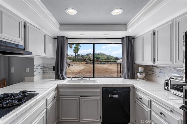kitchen featuring tile counters, a tray ceiling, a sink, and black appliances