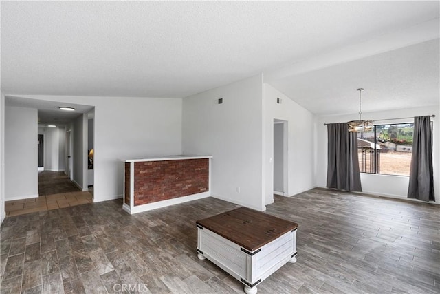 unfurnished living room featuring a textured ceiling, baseboards, a notable chandelier, lofted ceiling, and wood finished floors