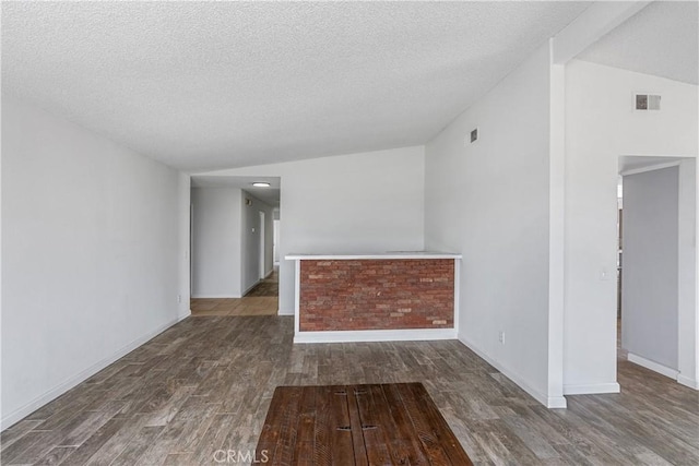 spare room with a textured ceiling, wood finished floors, visible vents, and baseboards