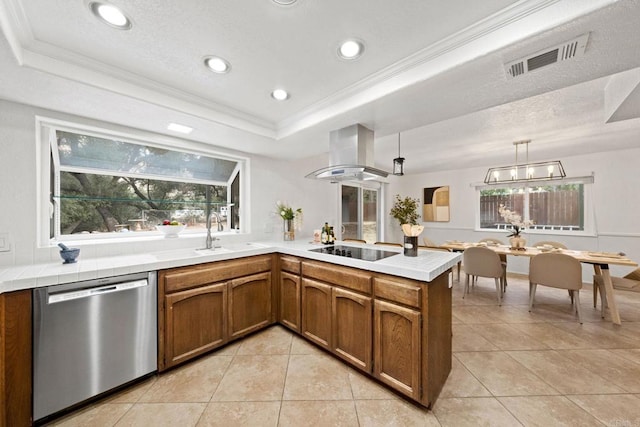 kitchen with wall chimney range hood, stainless steel dishwasher, a sink, a tray ceiling, and visible vents