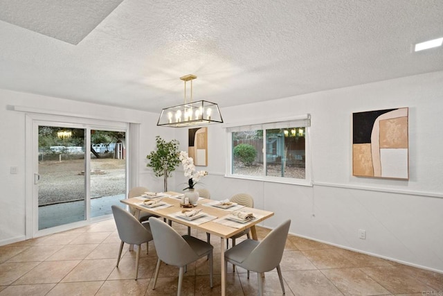 dining space with light tile patterned flooring, a chandelier, and a textured ceiling