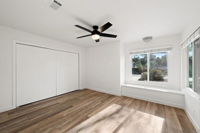 unfurnished bedroom featuring a ceiling fan, wood finished floors, a closet, baseboards, and visible vents