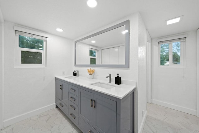 full bath featuring baseboards, a sink, recessed lighting, and double vanity