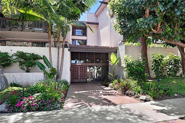view of front facade featuring stucco siding, a tiled roof, a gate, and a fenced front yard