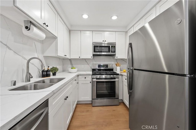 kitchen with white cabinets, backsplash, stainless steel appliances, and a sink