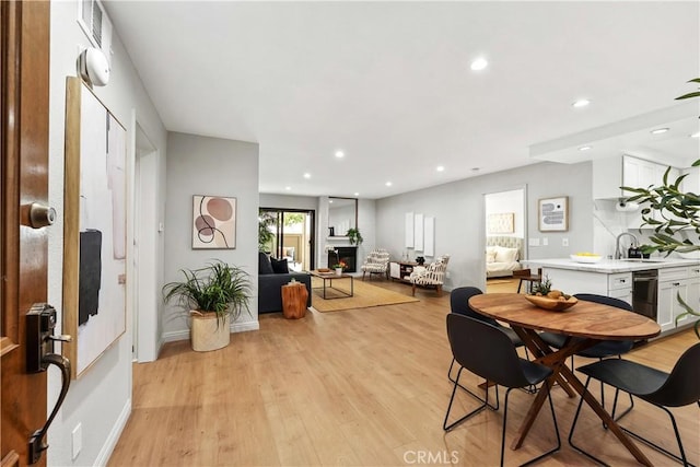dining room with light wood finished floors, baseboards, recessed lighting, and a lit fireplace