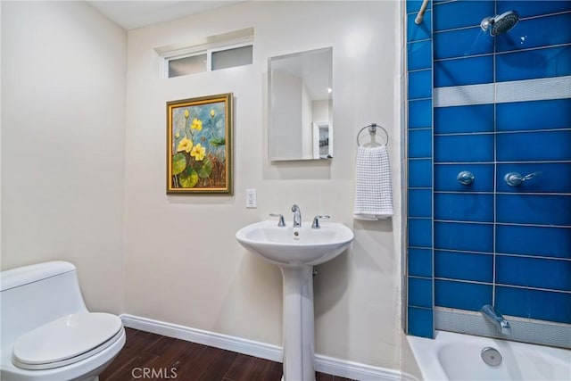 bathroom featuring wood finished floors, toilet, baseboards, and a sink