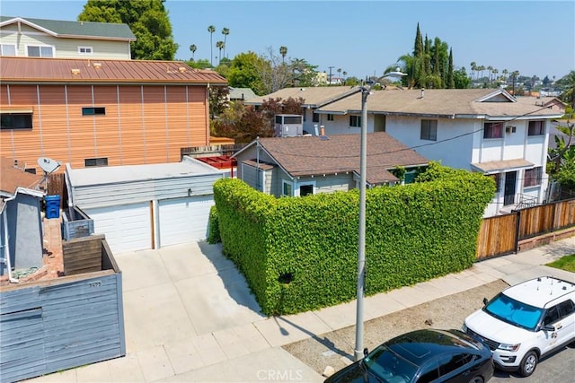 view of front of property with concrete driveway, an attached garage, fence, and a residential view
