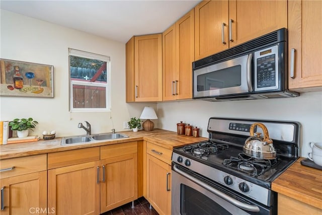 kitchen featuring wood counters, dark wood-type flooring, gas range, and a sink