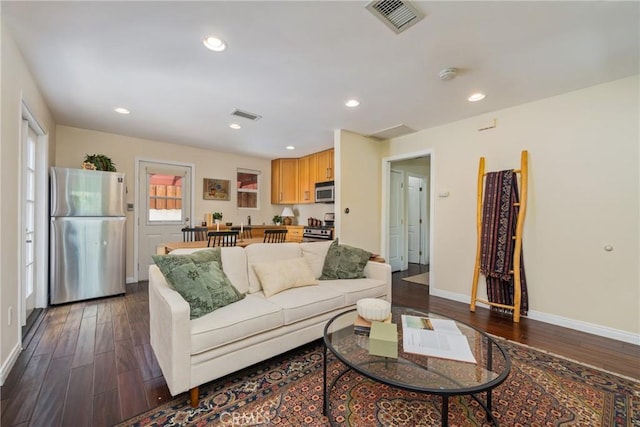 living room featuring baseboards, dark wood-type flooring, and visible vents