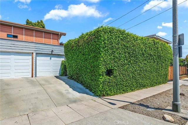 view of side of property with fence, driveway, and a garage