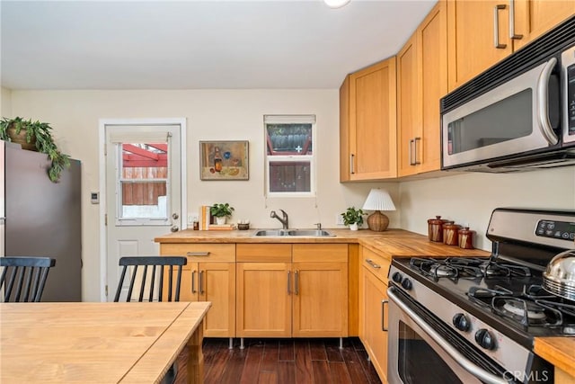 kitchen featuring butcher block countertops, dark wood-style floors, stainless steel appliances, and a sink