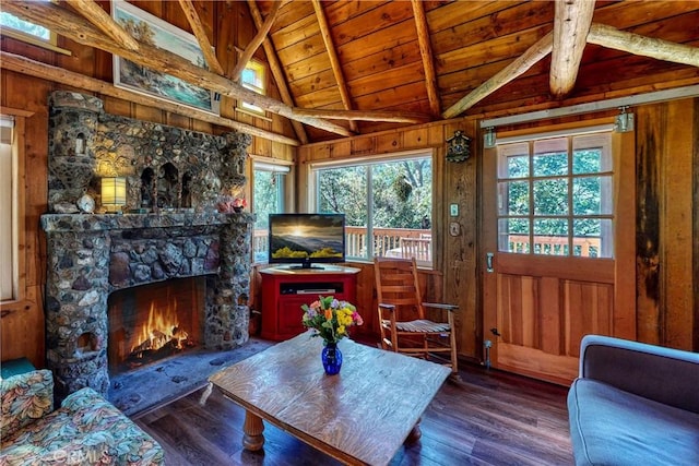 living room with vaulted ceiling with beams, wooden ceiling, wood walls, and a wealth of natural light