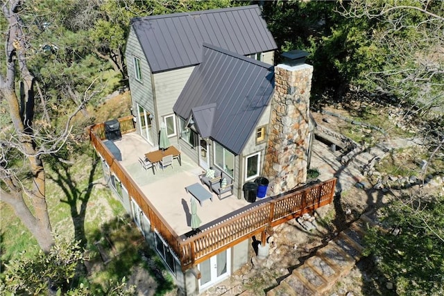 back of house featuring central AC unit, a standing seam roof, a wooden deck, a patio, and metal roof