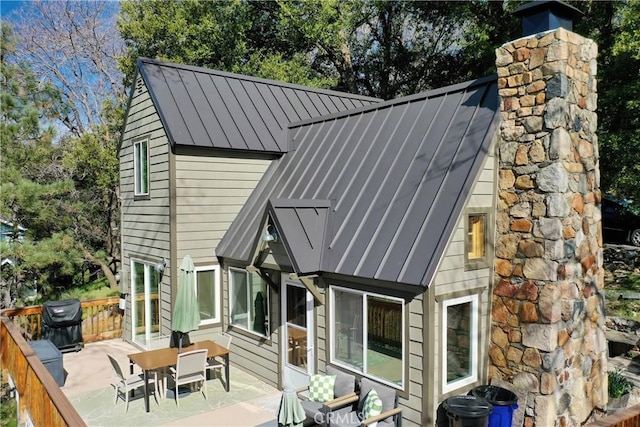 rear view of property with a standing seam roof, a patio area, and metal roof