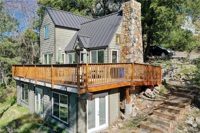 rear view of property with a wooden deck, a standing seam roof, french doors, and metal roof