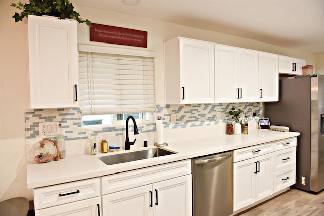 kitchen with white cabinets, appliances with stainless steel finishes, decorative backsplash, and a sink