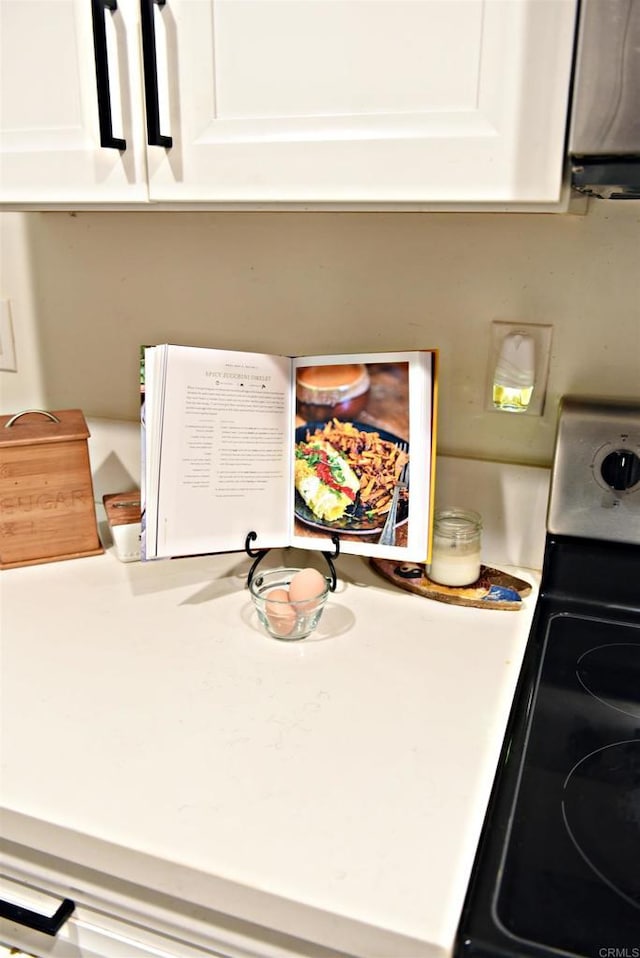 details featuring electric range, white cabinets, and light countertops