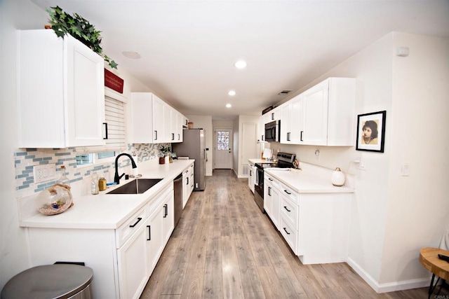 kitchen featuring white cabinets, baseboards, a sink, and appliances with stainless steel finishes