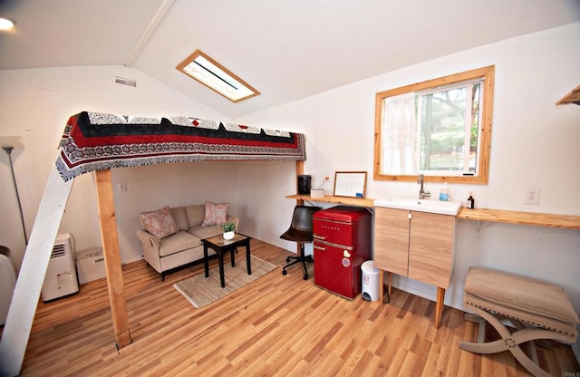 living area with lofted ceiling with skylight, visible vents, and light wood finished floors