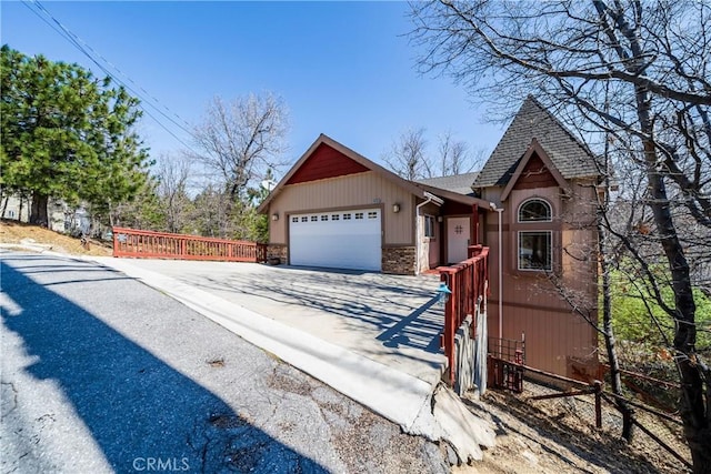 28136 N Bay Rd, Lake Arrowhead, CA 92352 - view of front facade with concrete driveway, a garage, a shingled roof, and stone siding