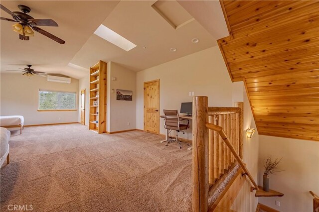 carpeted office space featuring lofted ceiling with skylight, ceiling fan, a wall mounted AC, and baseboards
