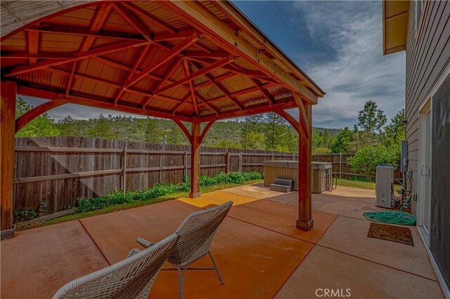 view of patio with a gazebo, a fenced backyard, and a hot tub