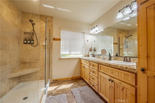 bathroom featuring double vanity, baseboards, a stall shower, and a sink