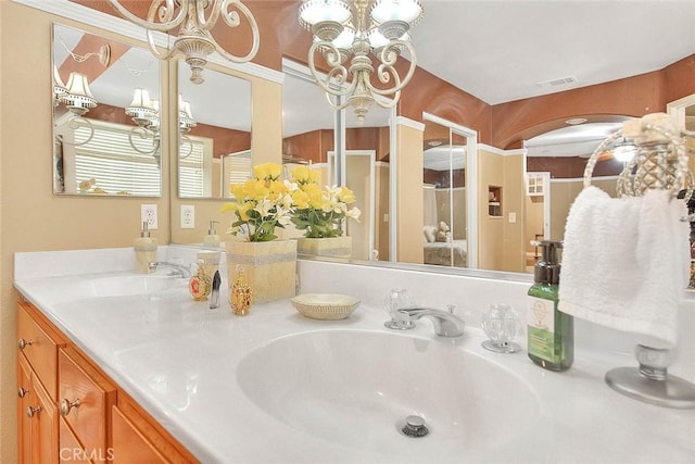 full bath with double vanity, visible vents, a sink, and an inviting chandelier